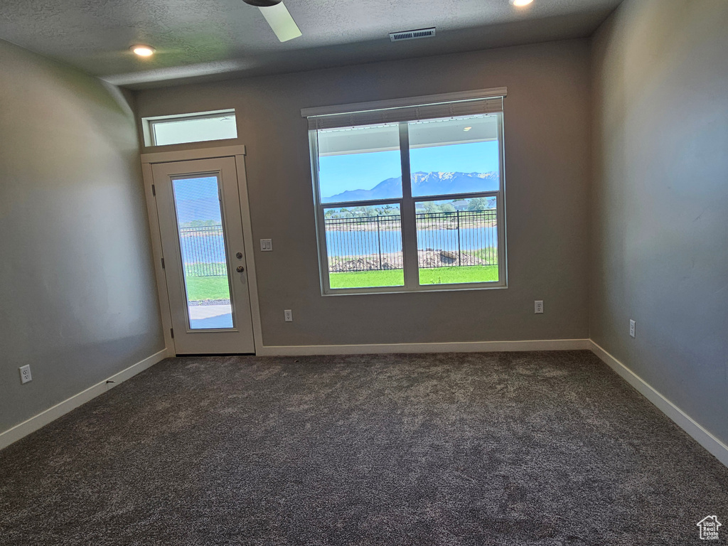 Unfurnished room with dark colored carpet, baseboards, and a textured ceiling