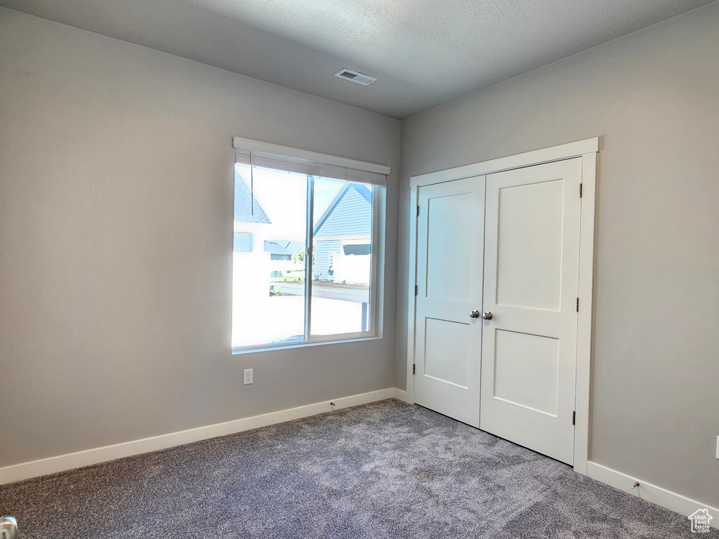 Unfurnished bedroom featuring carpet, baseboards, and a closet
