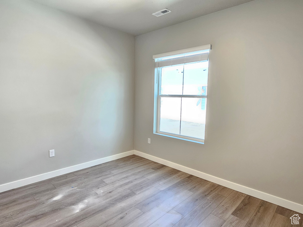 Unfurnished room featuring baseboards, healthy amount of natural light, and wood finished floors