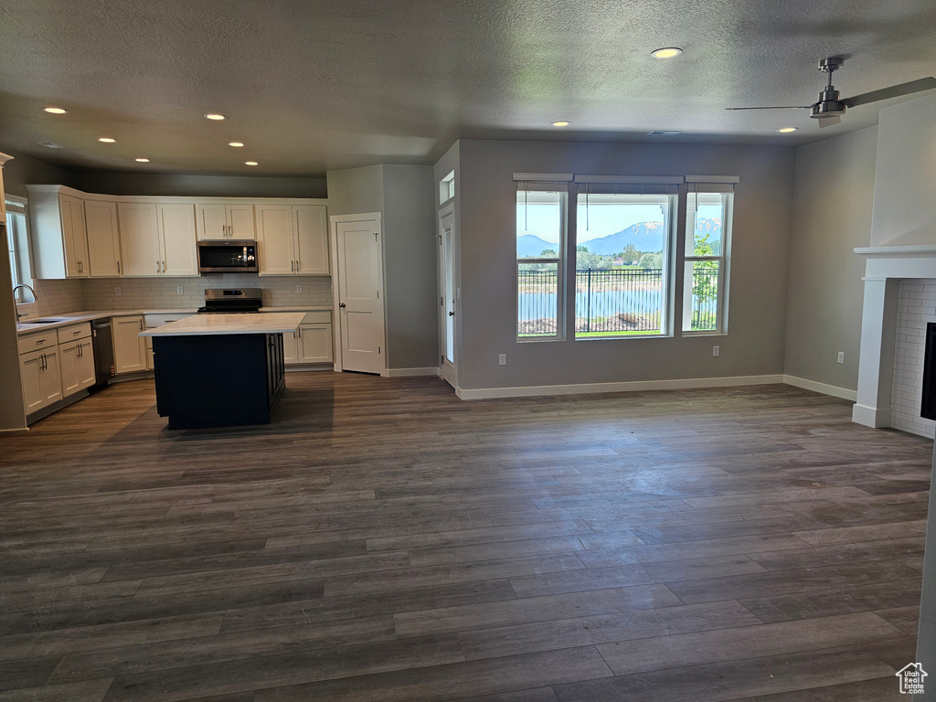 Kitchen with appliances with stainless steel finishes, open floor plan, a ceiling fan, a sink, and a textured ceiling