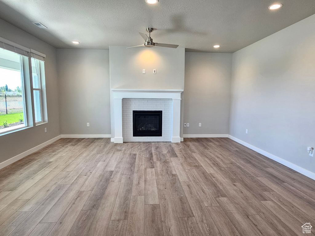 Unfurnished living room with ceiling fan, wood finished floors, recessed lighting, a brick fireplace, and baseboards