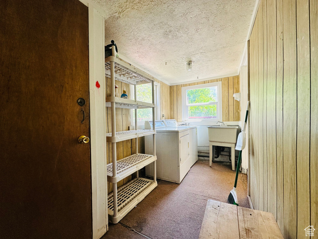 Clothes washing area with washer and dryer, carpet floors, wooden walls, and a textured ceiling