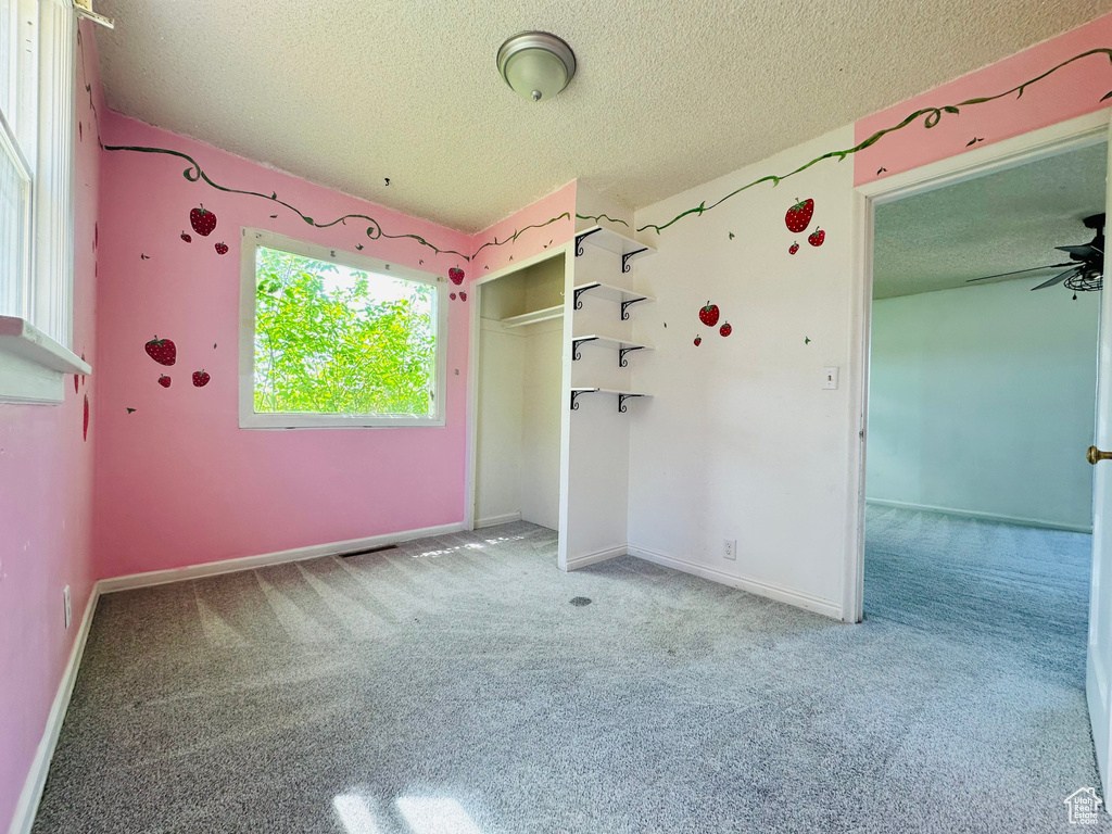 Unfurnished bedroom with a textured ceiling, carpet flooring, baseboards, and a closet