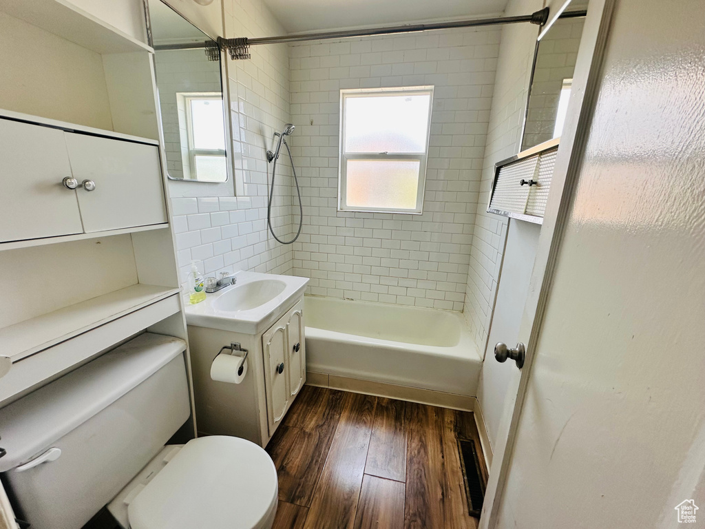 Full bathroom featuring wood finished floors, toilet, vanity, and shower / tub combination