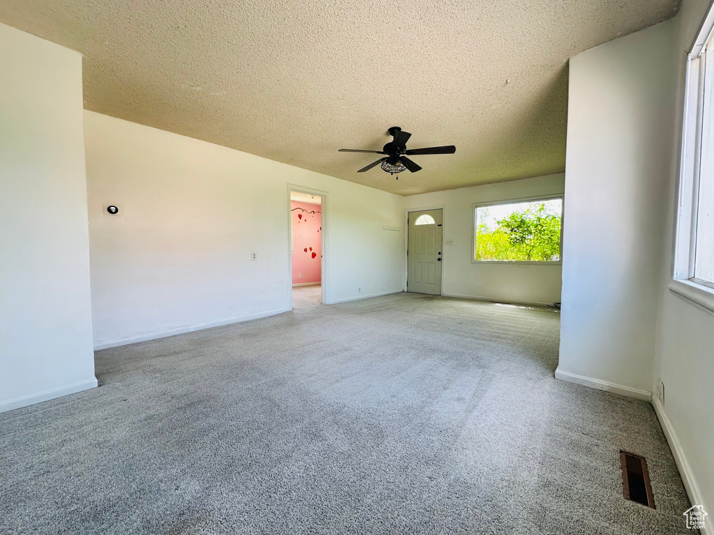 Unfurnished room with light carpet, a ceiling fan, a textured ceiling, and baseboards