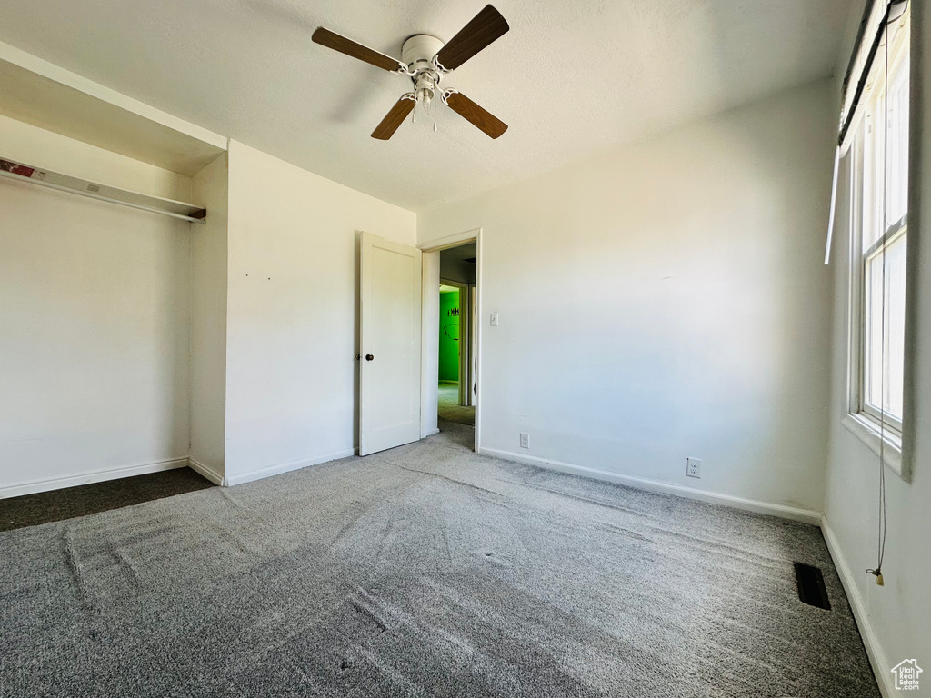 Unfurnished bedroom with carpet, baseboards, a ceiling fan, and a closet