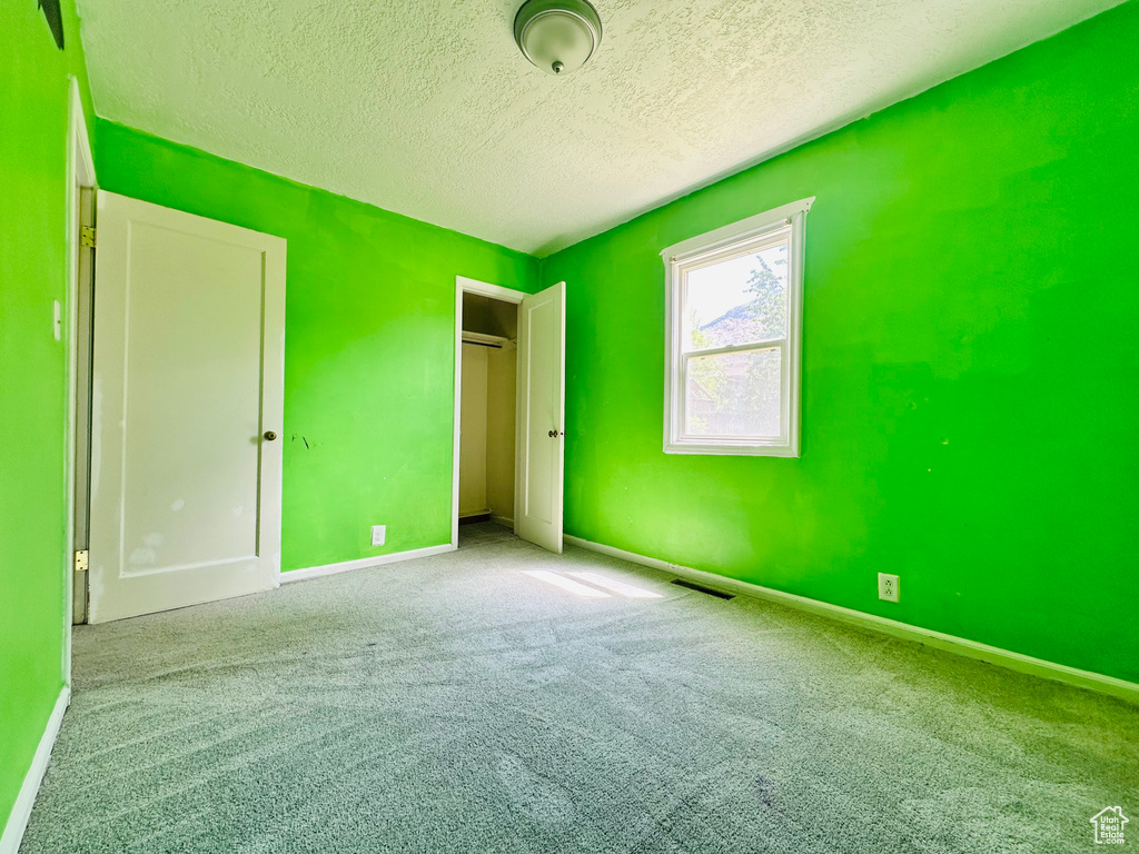 Unfurnished bedroom with carpet, a textured ceiling, and baseboards