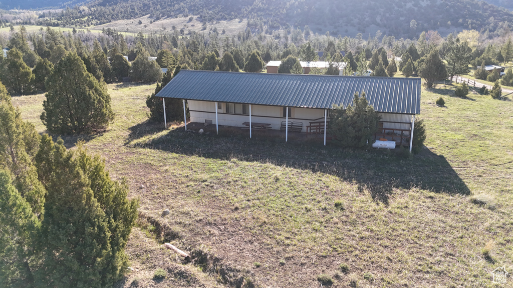 Aerial view of property and surrounding area featuring a heavily wooded area and mountains