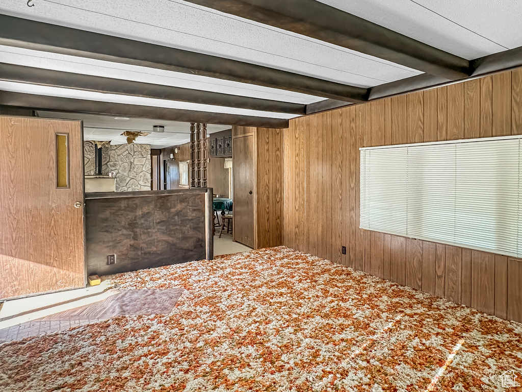 Bedroom with wood walls and beamed ceiling