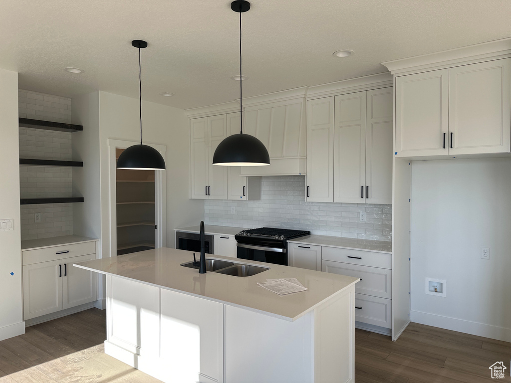 Kitchen featuring open shelves, range with gas stovetop, a sink, light wood-style floors, and recessed lighting