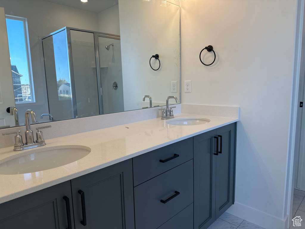 Full bath featuring a shower stall, double vanity, and baseboards