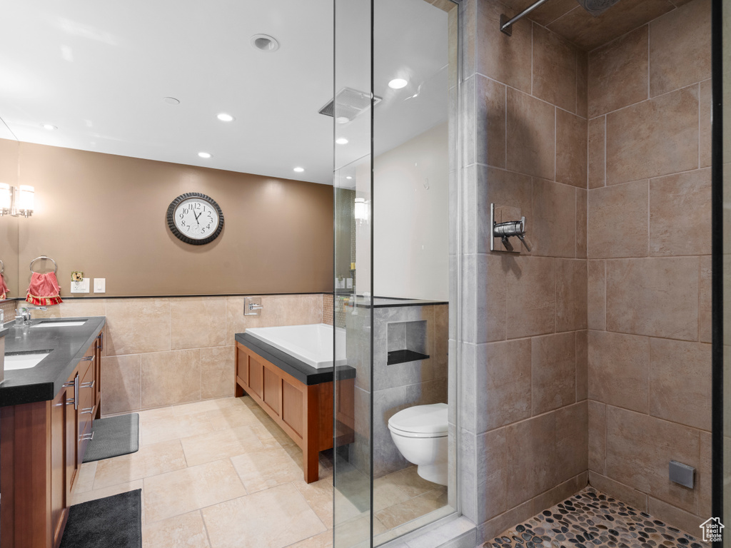 Bathroom featuring tile walls, a tile shower, double vanity, recessed lighting, and tile patterned flooring