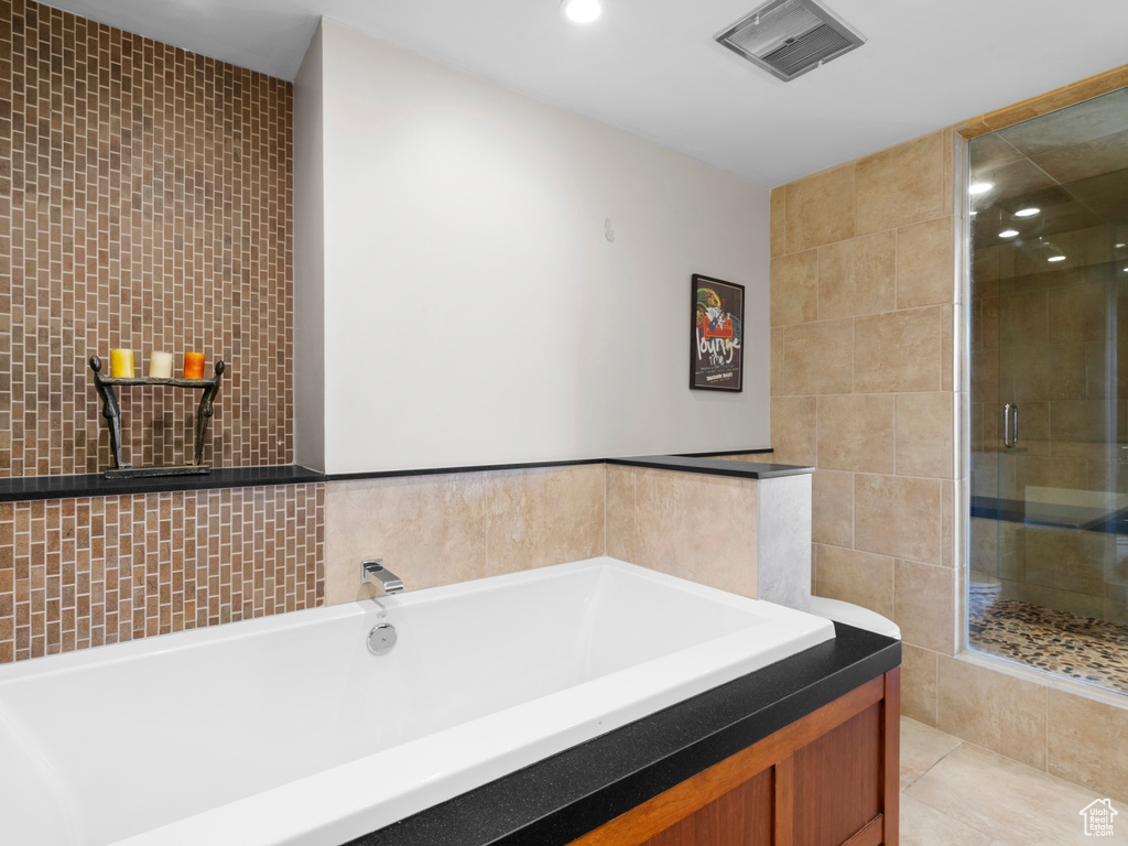 Full bathroom with tile walls, a stall shower, a tub to relax in, and recessed lighting