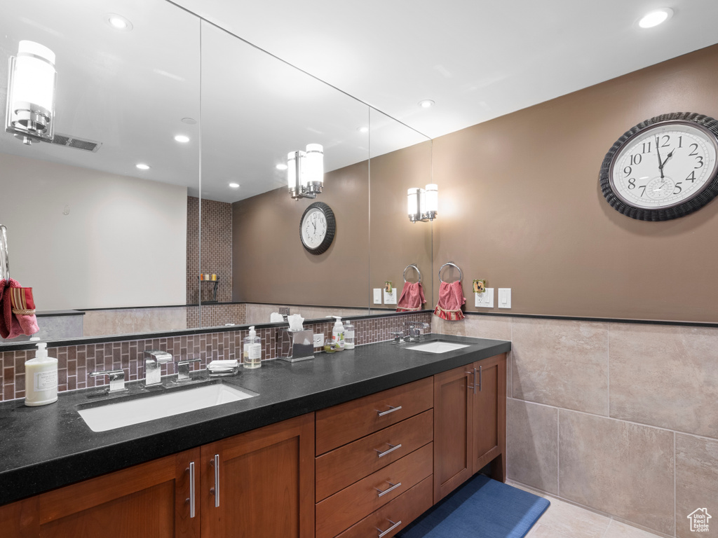 Bathroom featuring double vanity, recessed lighting, tile walls, and a wainscoted wall