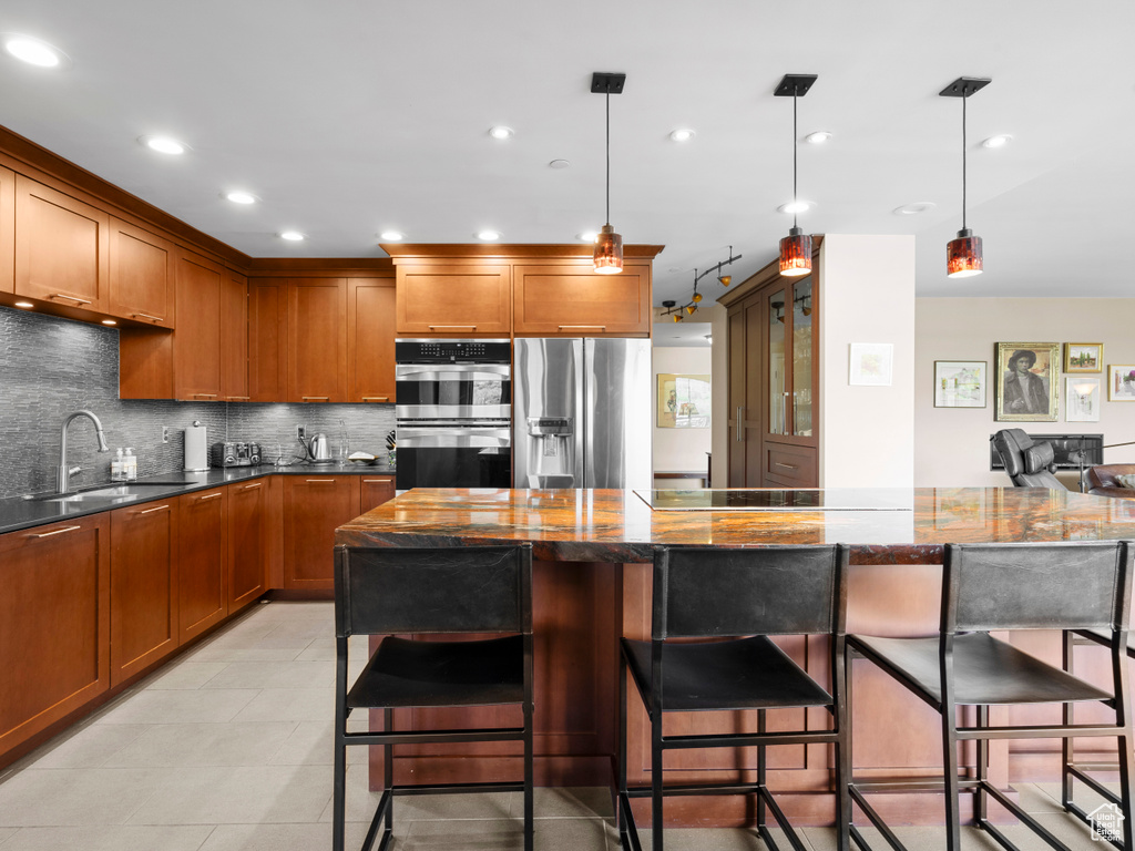 Kitchen featuring a sink, stainless steel appliances, brown cabinets, backsplash, and recessed lighting