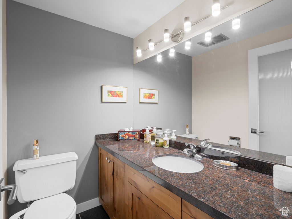 Half bath with toilet, vanity, and baseboards