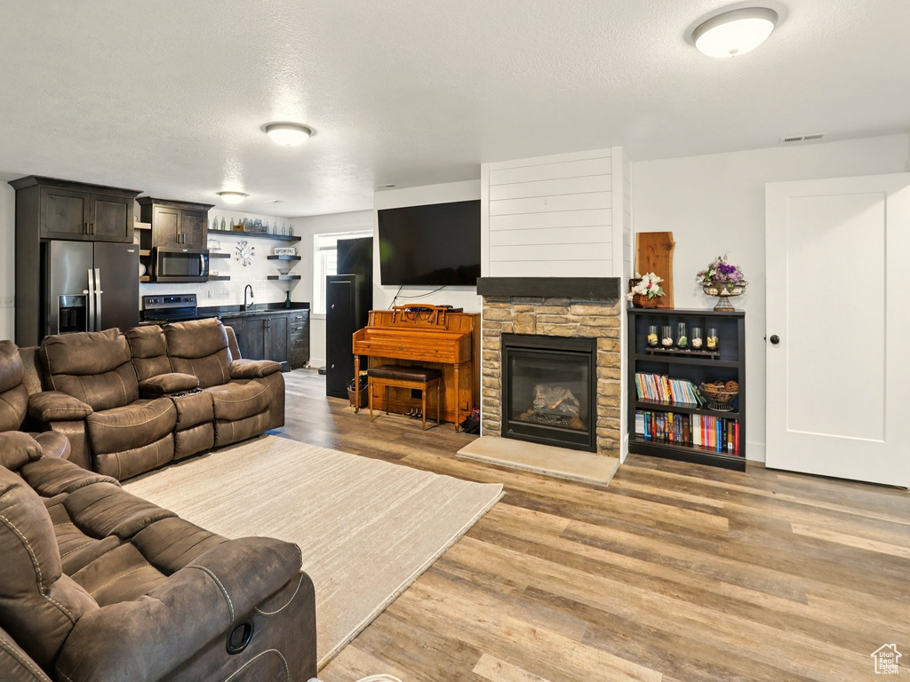 Living area with wet bar, light wood-style floors, a textured ceiling, and a fireplace