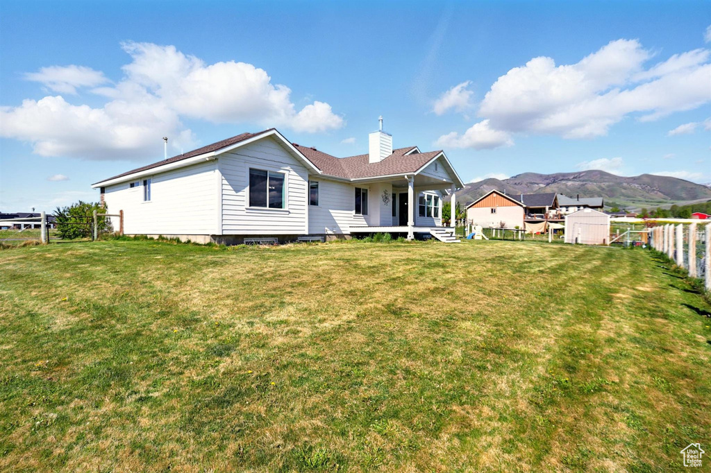 Back of property with a chimney, covered porch, a shed, a mountain view, and an outdoor structure