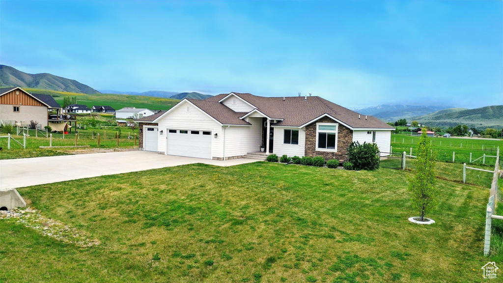 Single story home featuring a mountain view, stone siding, an attached garage, and concrete driveway