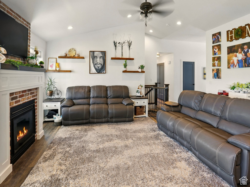 Living area with a ceiling fan, a brick fireplace, dark wood finished floors, lofted ceiling, and recessed lighting