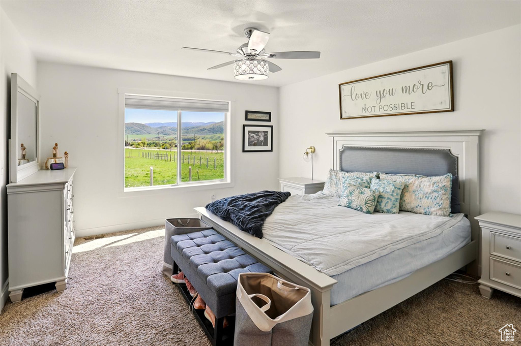 Carpeted bedroom featuring ceiling fan and a mountain view