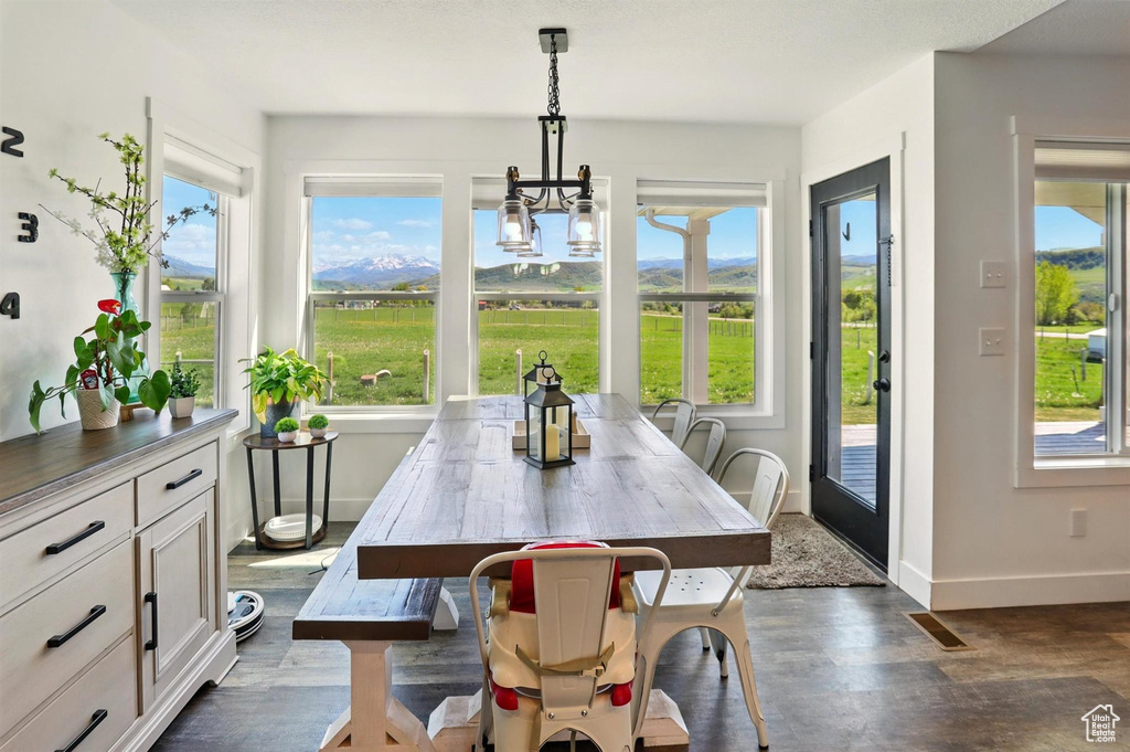 Dining area with healthy amount of natural light, dark wood-style flooring, baseboards, and a chandelier