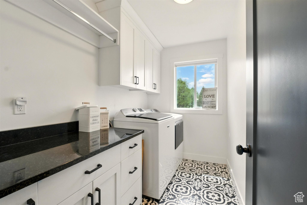 Laundry room featuring independent washer and dryer, baseboards, and cabinet space