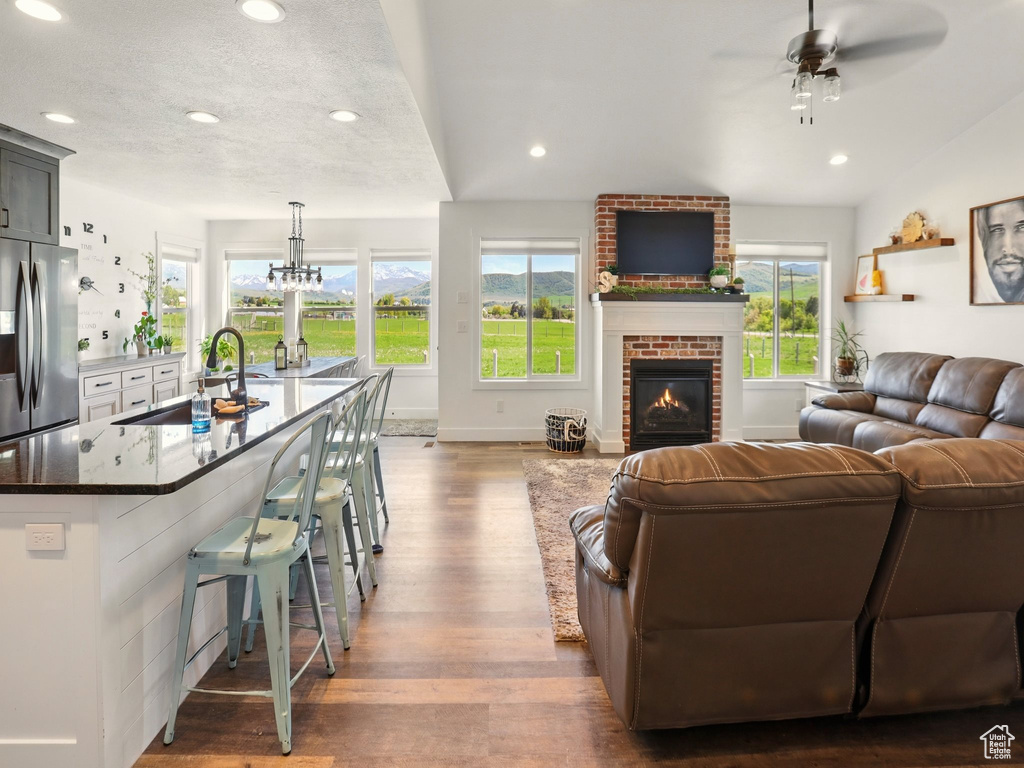 Living area featuring dark wood finished floors, ceiling fan, a fireplace, recessed lighting, and baseboards