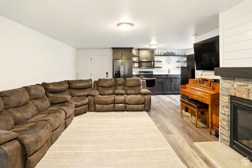 Living room featuring a stone fireplace, wet bar, and light wood-style floors