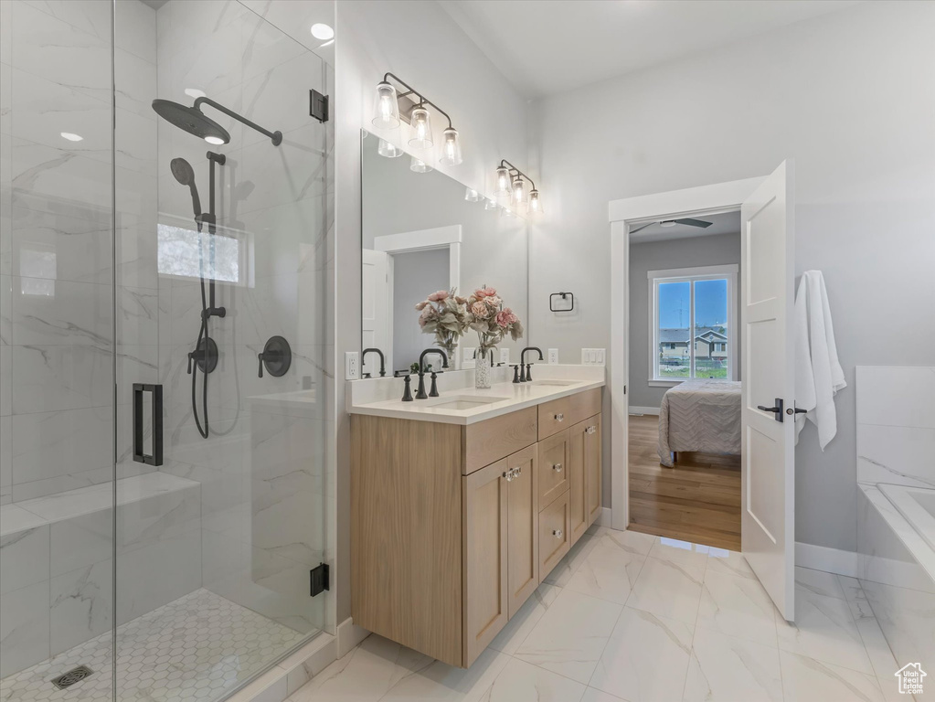 Full bathroom featuring marble look tile flooring, a stall shower, baseboards, and double vanity