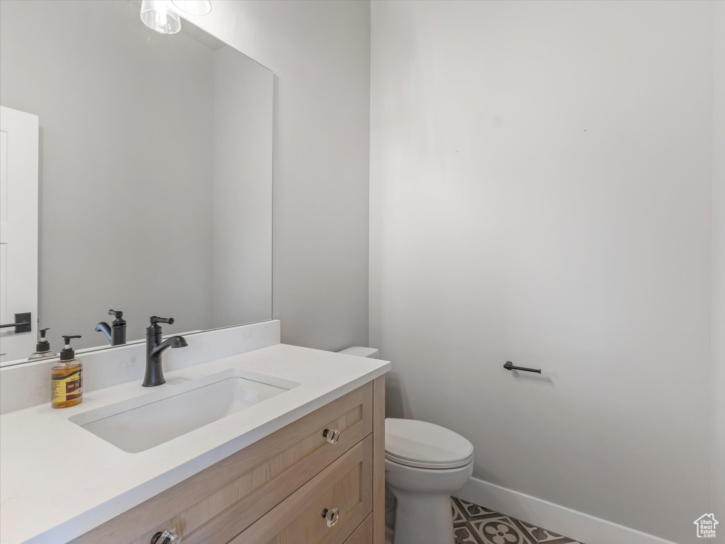 Bathroom with toilet, vanity, and baseboards