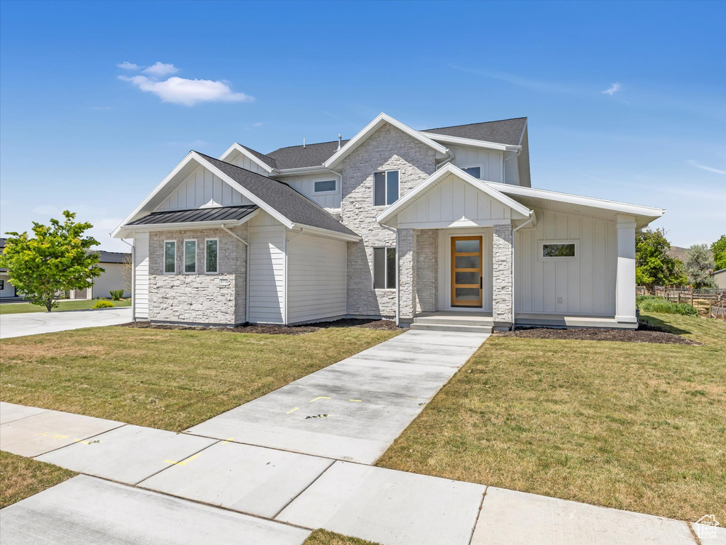View of front of property featuring stone siding, board and batten siding, and a front lawn