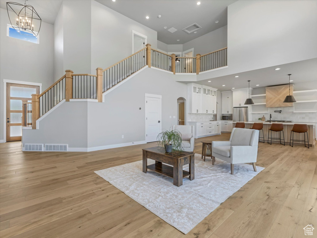 Living room with a towering ceiling, light wood-style floors, stairway, recessed lighting, and baseboards