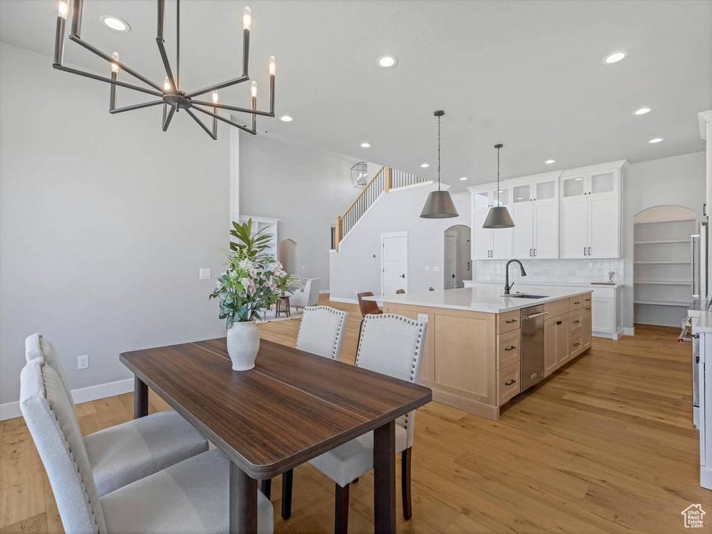 Dining space with light wood-style floors, recessed lighting, arched walkways, baseboards, and a chandelier