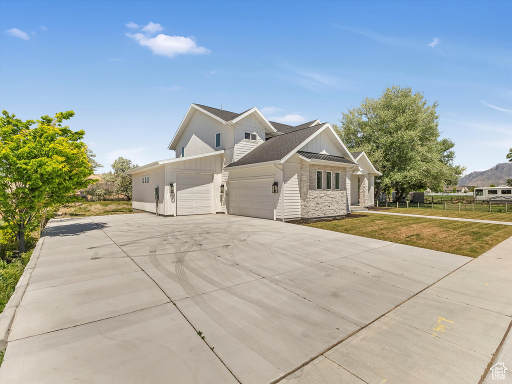 View of property exterior featuring a garage, board and batten siding, driveway, a lawn, and roof with shingles