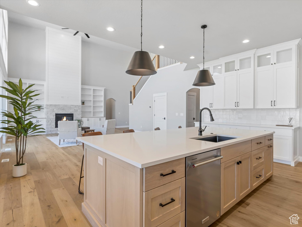 Kitchen with a sink, stainless steel dishwasher, arched walkways, light wood-type flooring, and recessed lighting