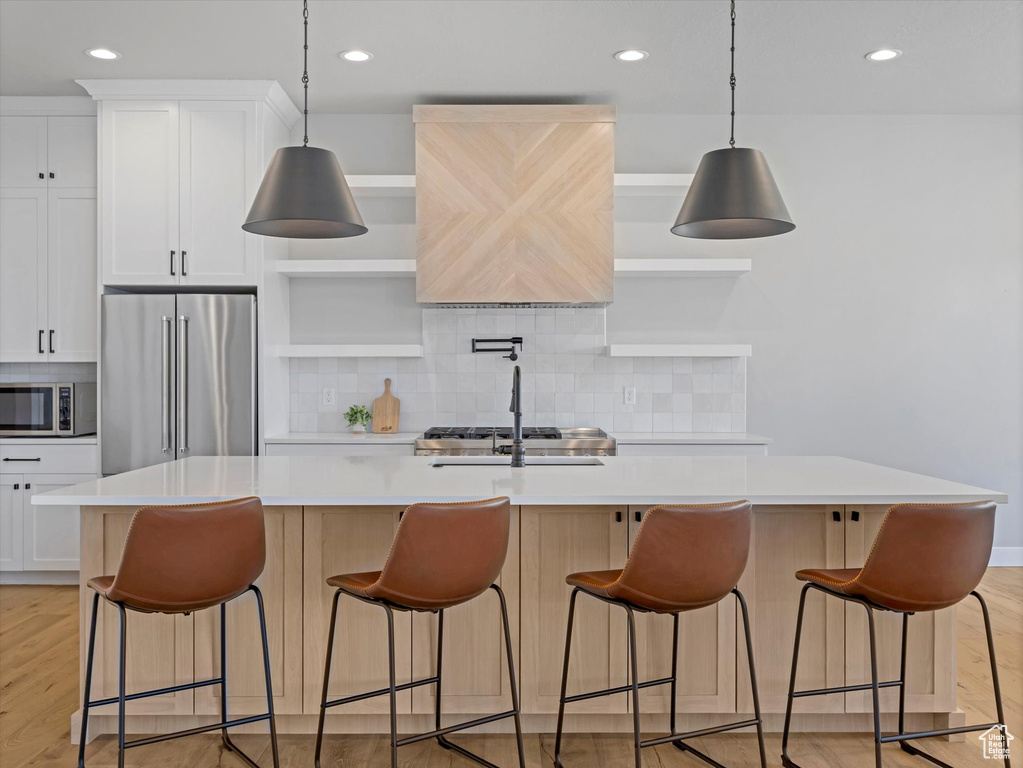 Kitchen with appliances with stainless steel finishes, a kitchen island with sink, light countertops, tasteful backsplash, and recessed lighting