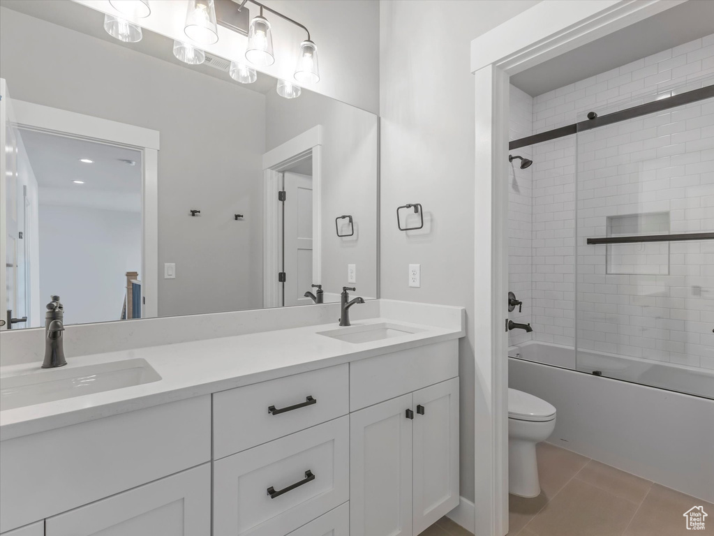 Full bath featuring toilet, double vanity, combined bath / shower with glass door, and tile patterned floors