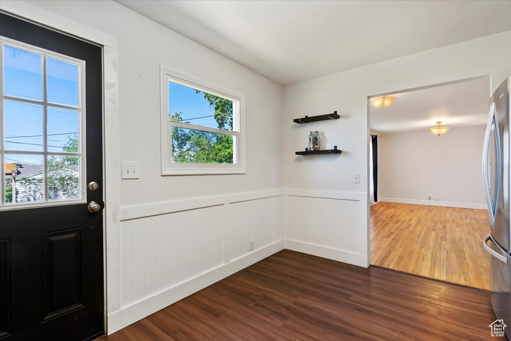 Foyer with dark wood-style flooring and a wainscoted wall