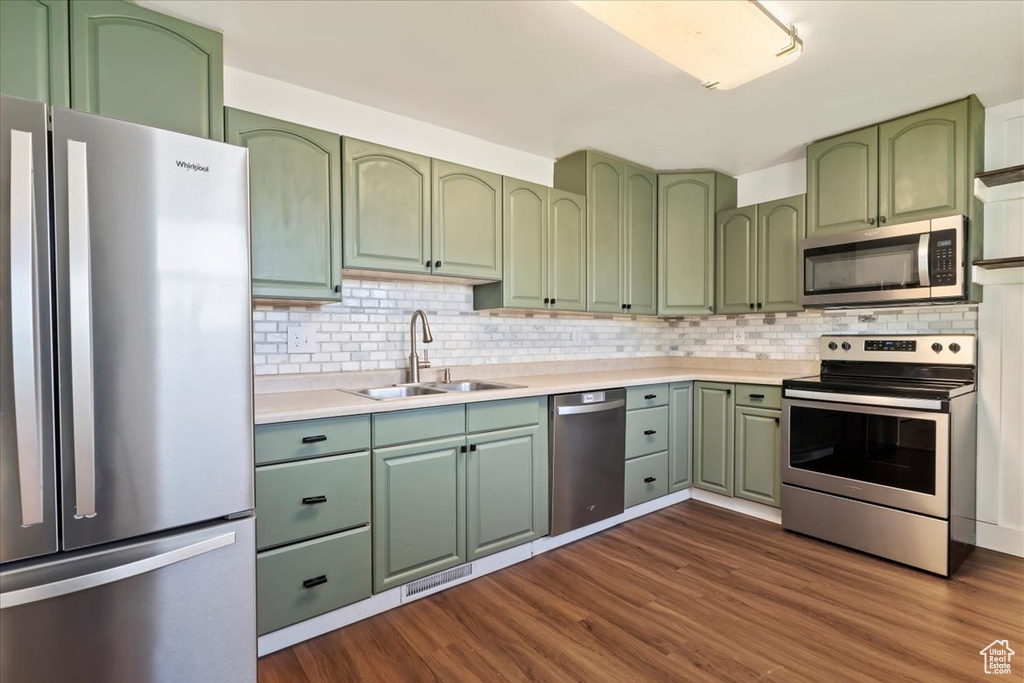 Kitchen featuring green cabinets, appliances with stainless steel finishes, a sink, and light countertops