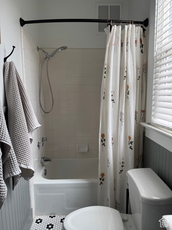 Bathroom with shower / bath combo with shower curtain, toilet, and tile patterned flooring