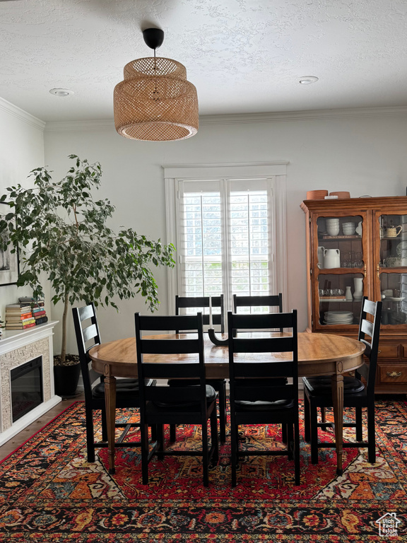 Dining area featuring a textured ceiling, ornamental molding, and a glass covered fireplace