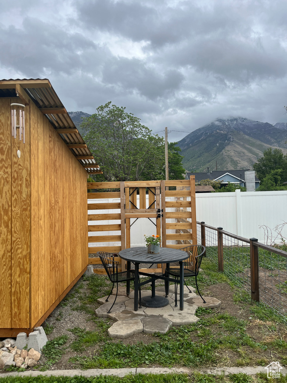 View of yard with a mountain view, outdoor dining space, fence, and a patio