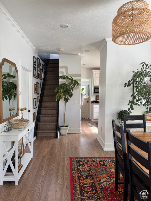 Hallway featuring wood finished floors, stairway, a textured ceiling, baseboards, and ornamental molding
