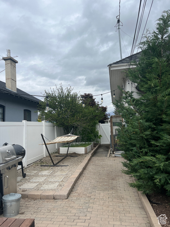 View of patio featuring a gate, fence, and a grill