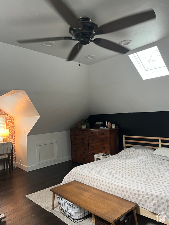 Bedroom featuring lofted ceiling, a skylight, wood finished floors, and baseboards