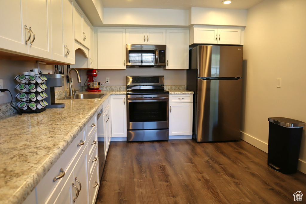 Kitchen featuring appliances with stainless steel finishes, a sink, recessed lighting, white cabinetry, and dark wood-style floors