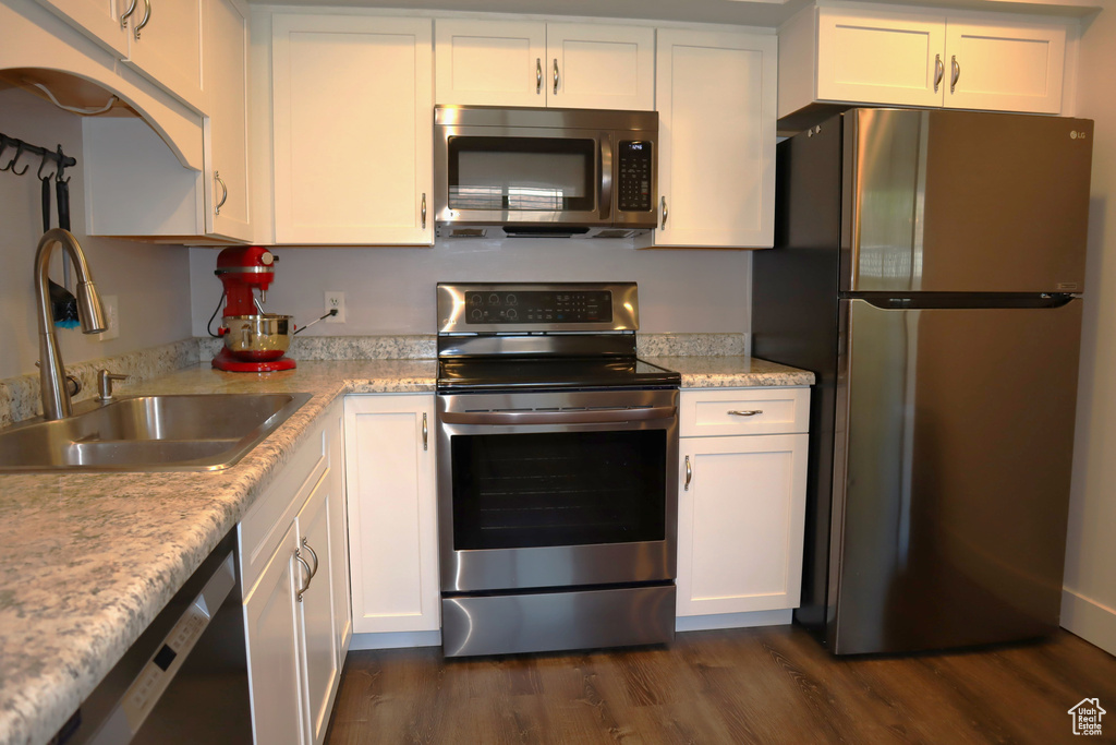 Kitchen featuring appliances with stainless steel finishes, a sink, dark wood-style floors, and white cabinets
