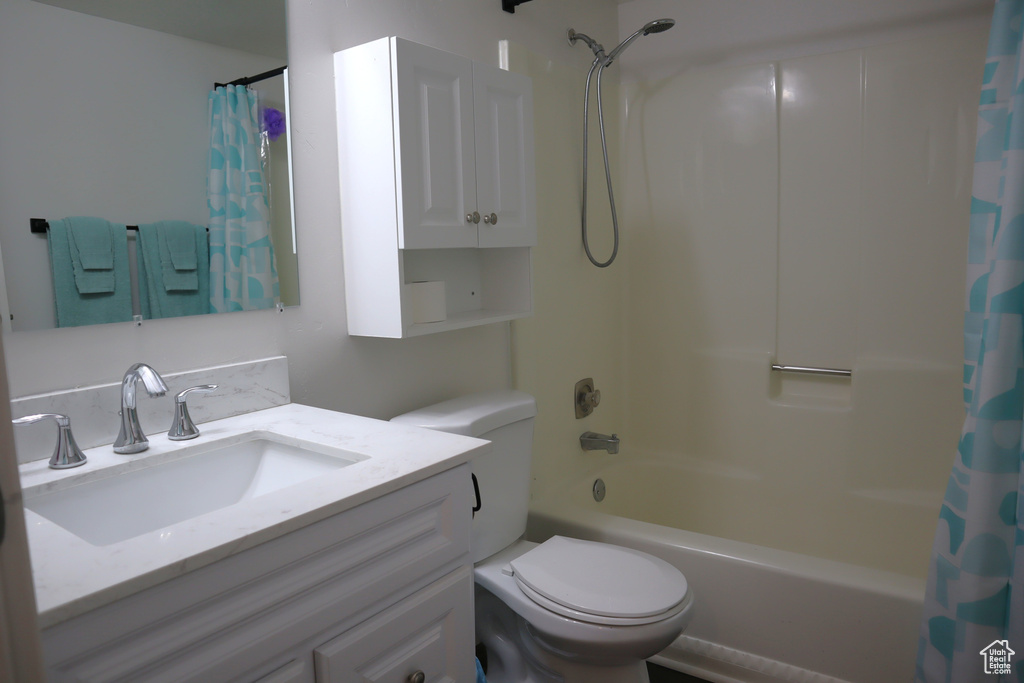 Bathroom featuring shower / bath combination with curtain, toilet, and vanity