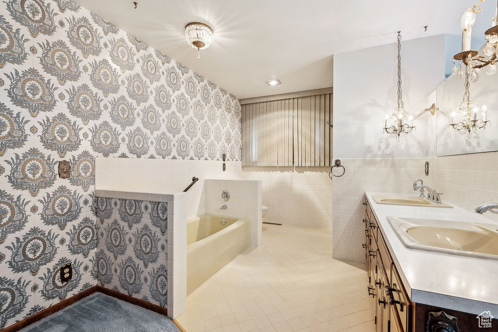 Bathroom featuring wallpapered walls, a bath, double vanity, toilet, and tile patterned flooring
